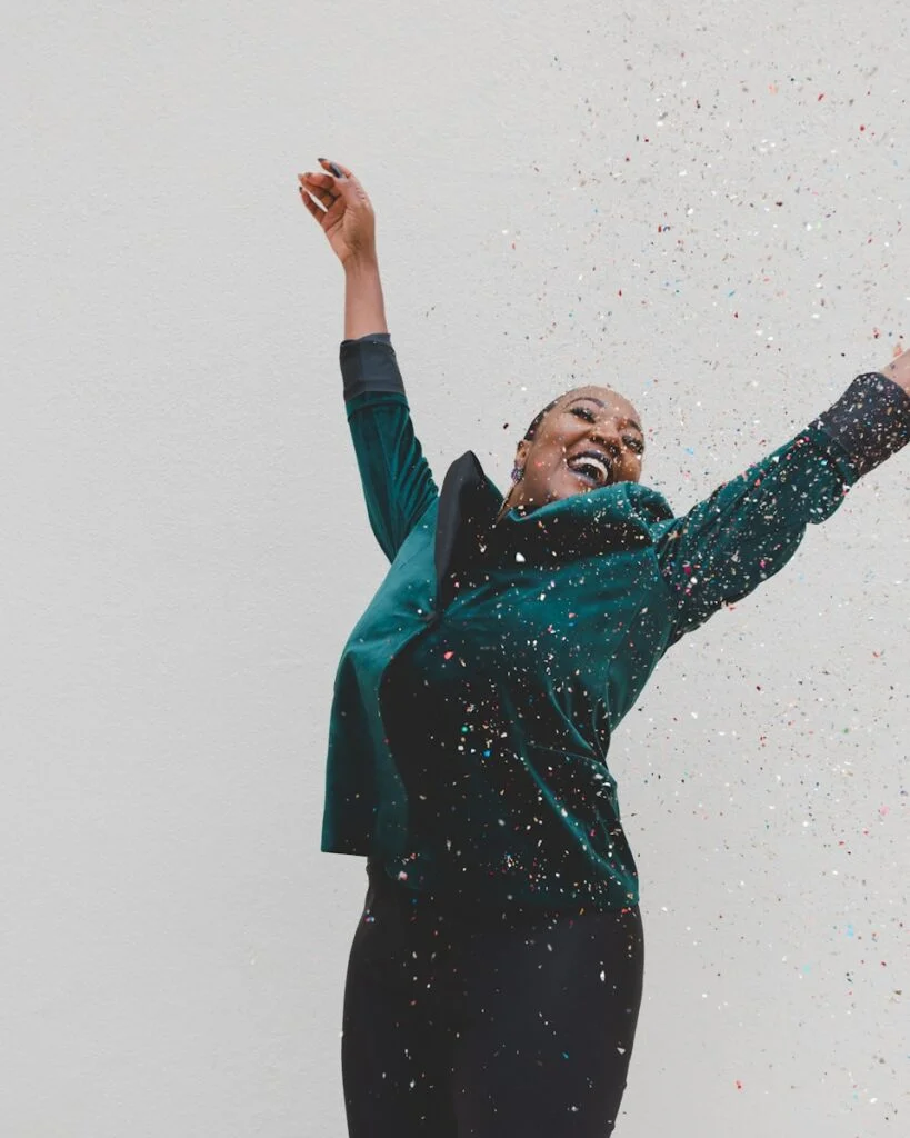 Overcoming Burnout: Rediscovering Joy in Your Work 4 | Mania Africa | maniainc.com A woman in a green jacket raising her hands - Overcoming Burnout: Rediscovering Joy in Your Work - Mania Work