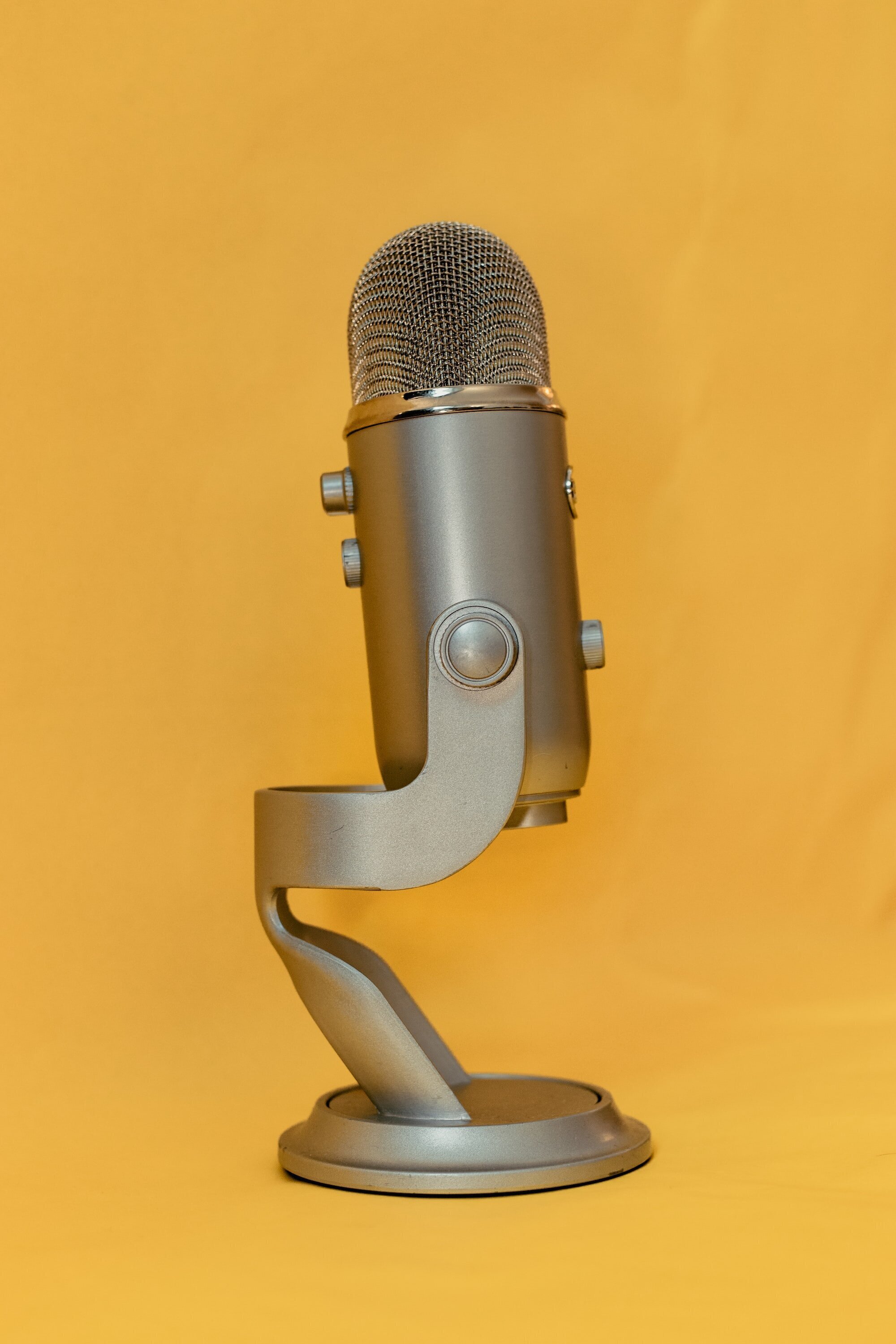 Dictation Blogging or Dicta Blogging: How to Write with Your Voice and Type Faster 3 | Mania Africa | maniainc.com A microphone on its stand with a yellow background