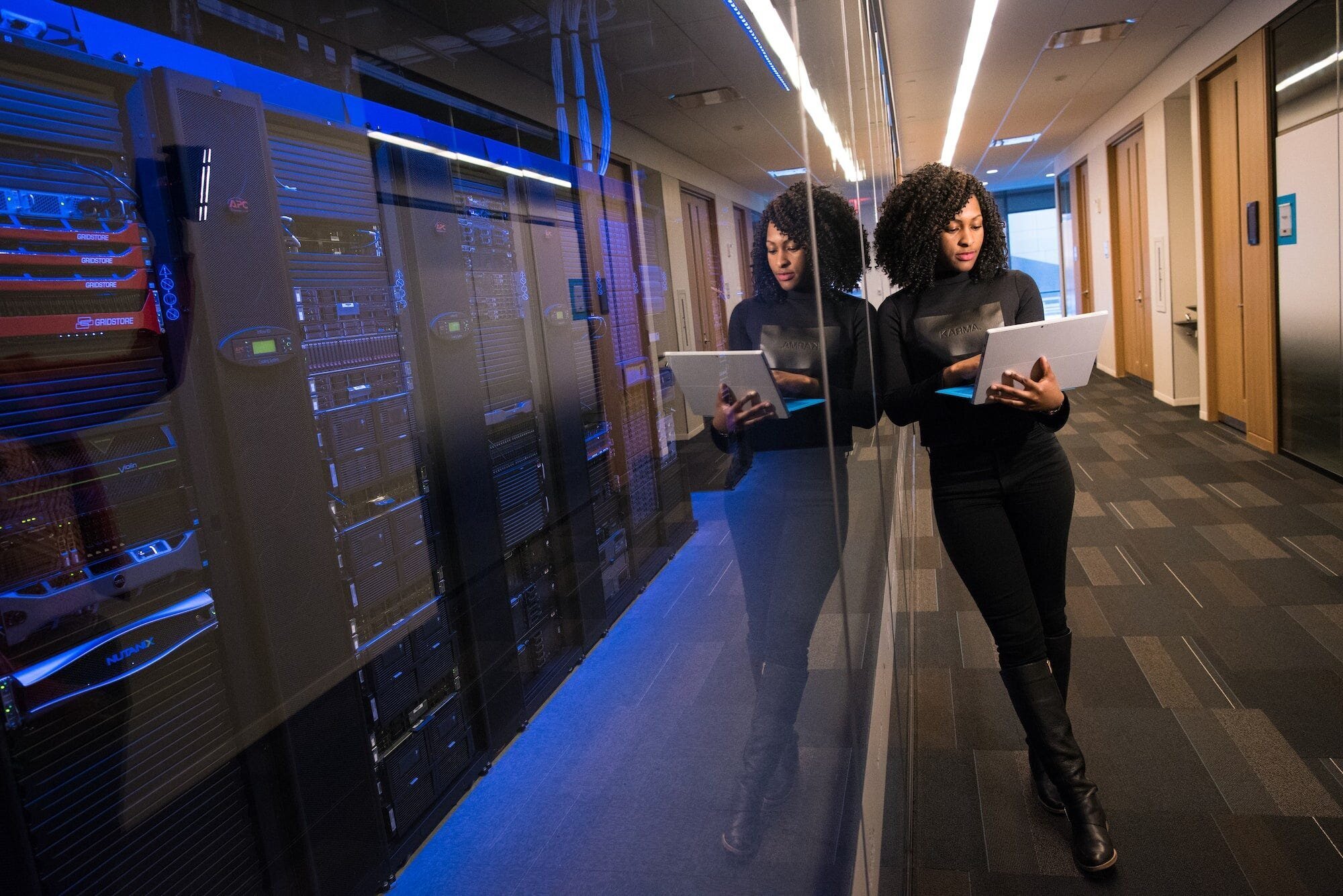 Maximizing Your WordPress Site's Performance: 7 Essential Optimization Techniques 2 | Mania Africa | maniainc.com An image of a woman standing outside the glass wall of a server room with her laptop