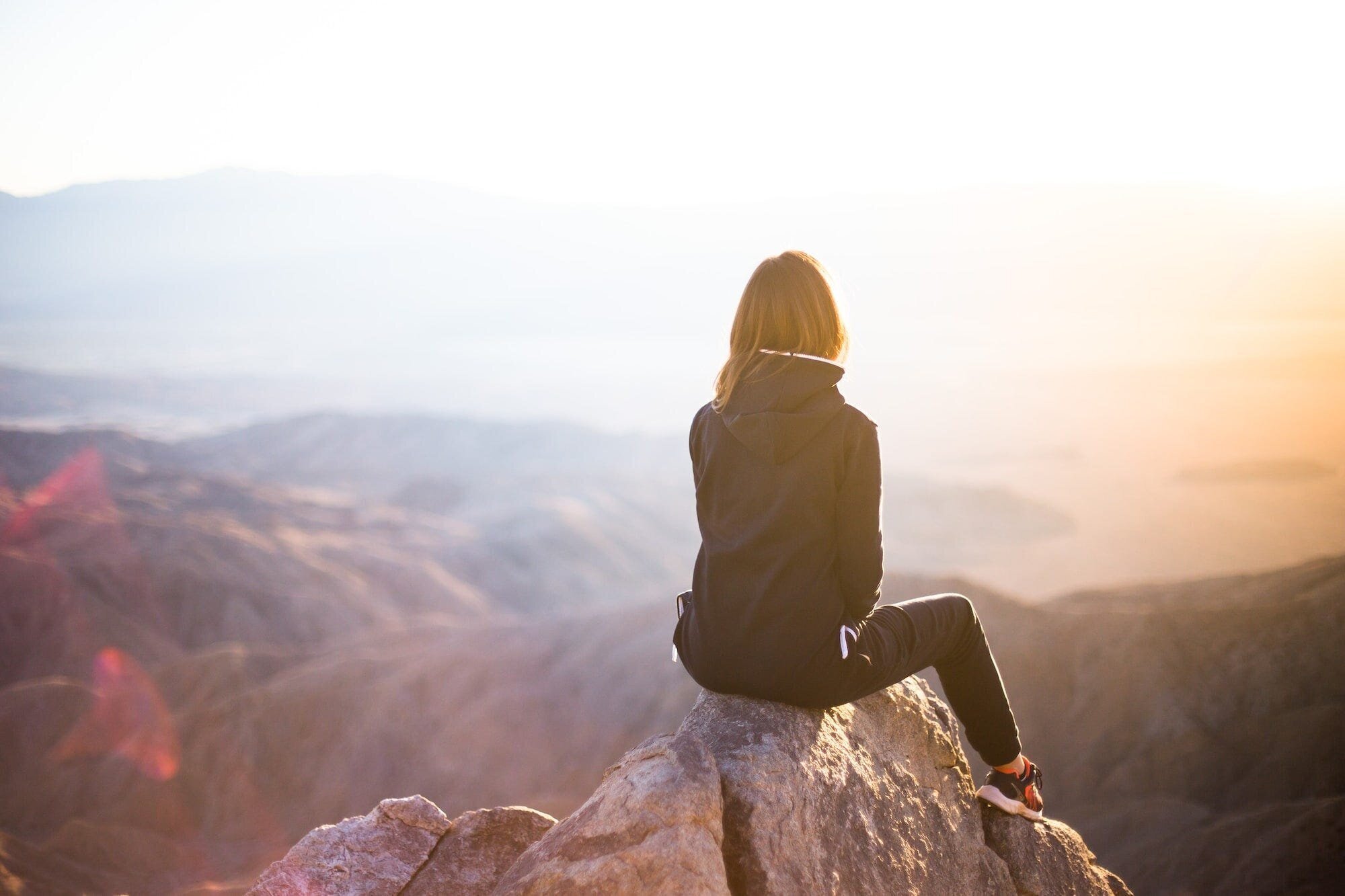 Mental Health: The Importance of Prioritizing Your Well-Being 3 | Mania Africa | maniainc.com A photo of a woman seating on a rock on top of a mountain range