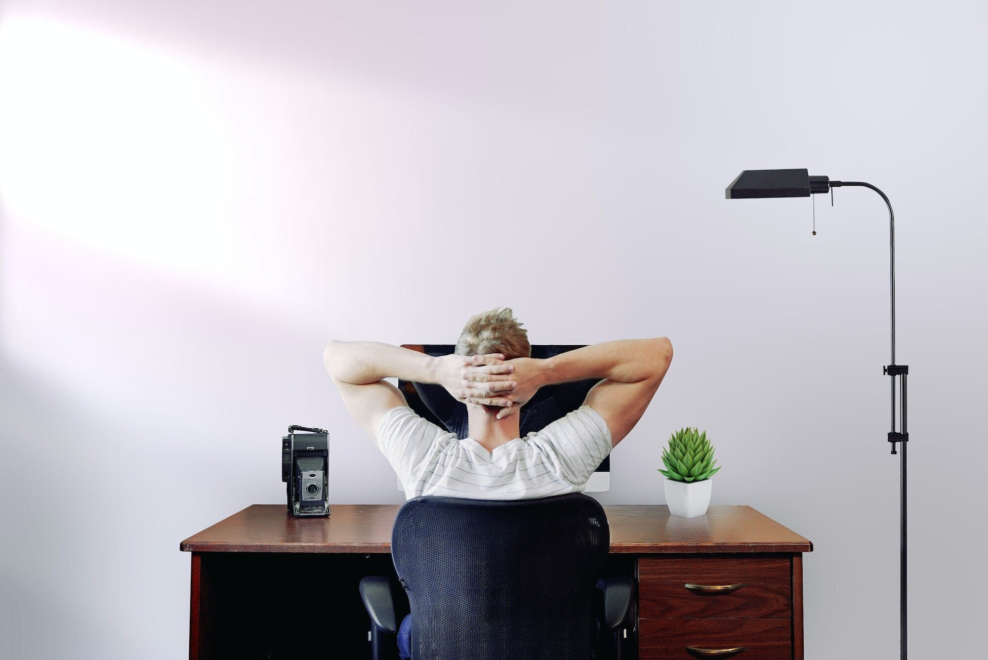 Remotasks Review: Everything You Need to Know About the Micro-Job Site for Remote Work Opportunities 6 | Mania Africa | maniainc.com An image of a man sitting on his desk looking at his computer with his hands behind his head