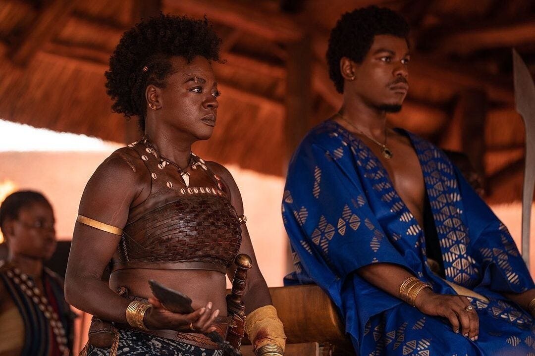 The Woman King Movie Review and Summary 8 | Mania Africa | maniainc.com Nanisca as the woman king seated beside king Ghezo