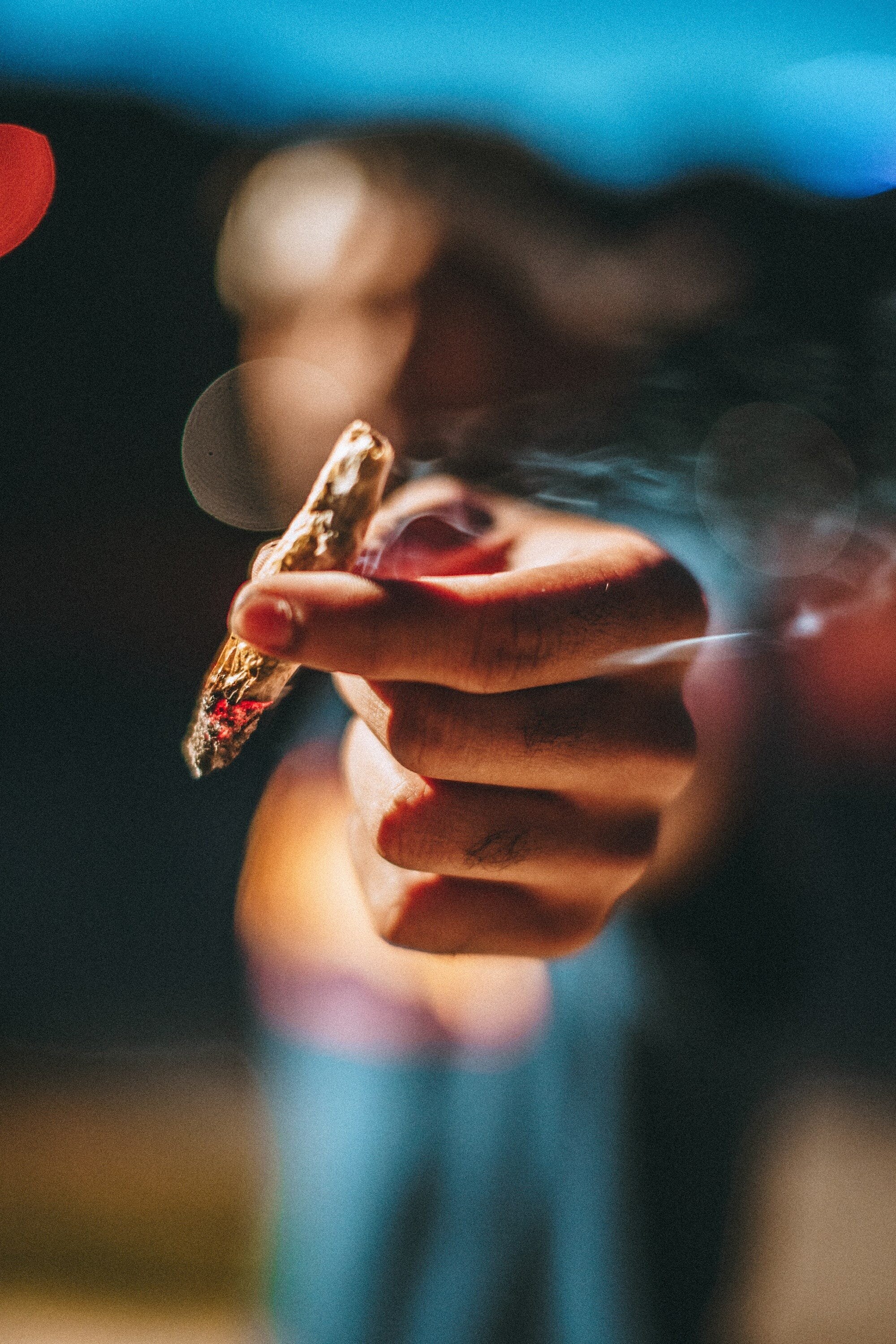 Health Benefits and Potential Risks of Cannabis: What You Need to Know 4 | Mania Africa | maniainc.com An image of a blurred out man handing someone else a cannabis cigarette