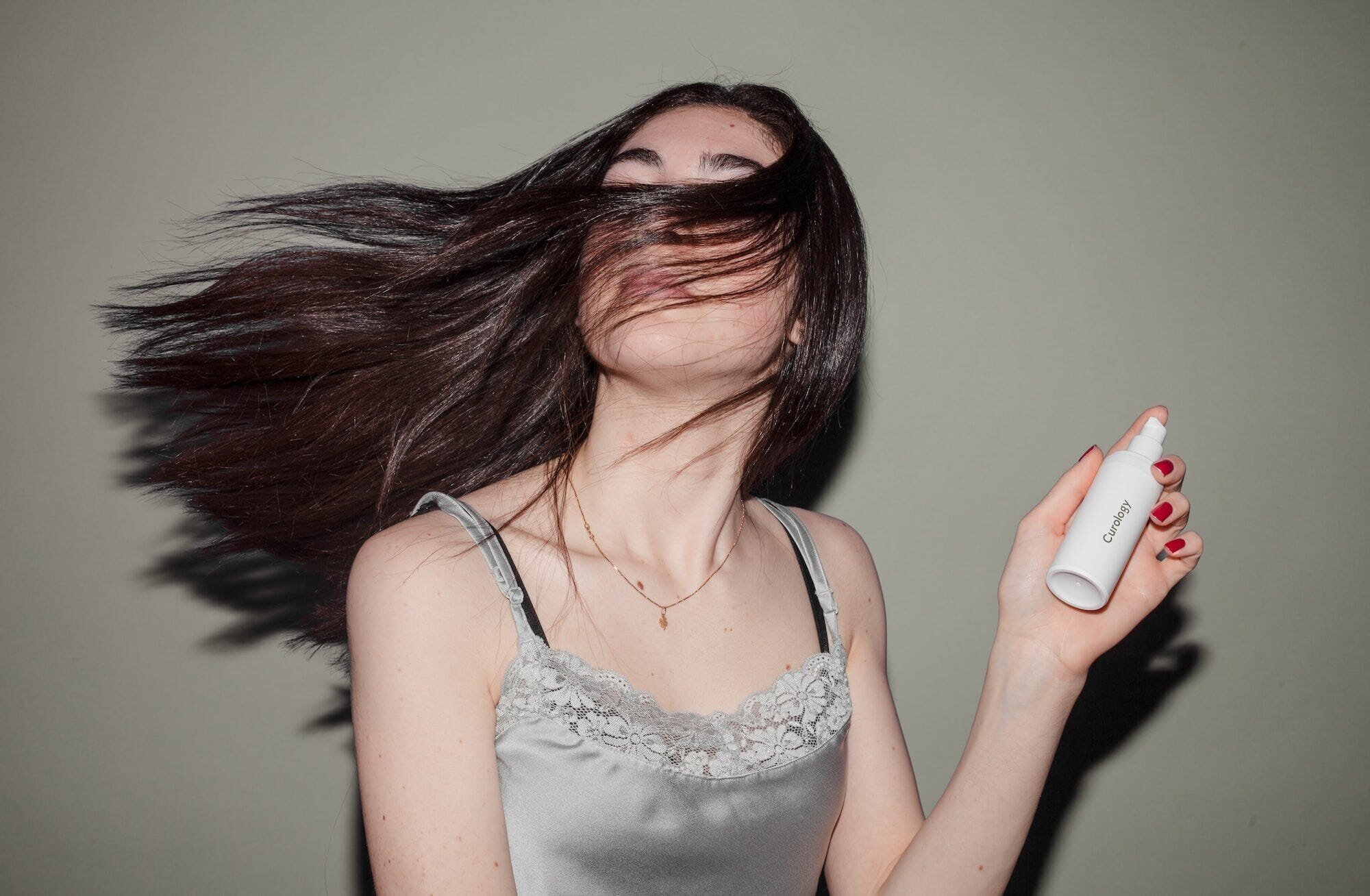 Unlock the Secret to Healthy and Shiny Locks: The Ultimate Hair Care Routine 4 | Mania Africa | maniainc.com A woman swaying her hair while holding a bottle of hair product
