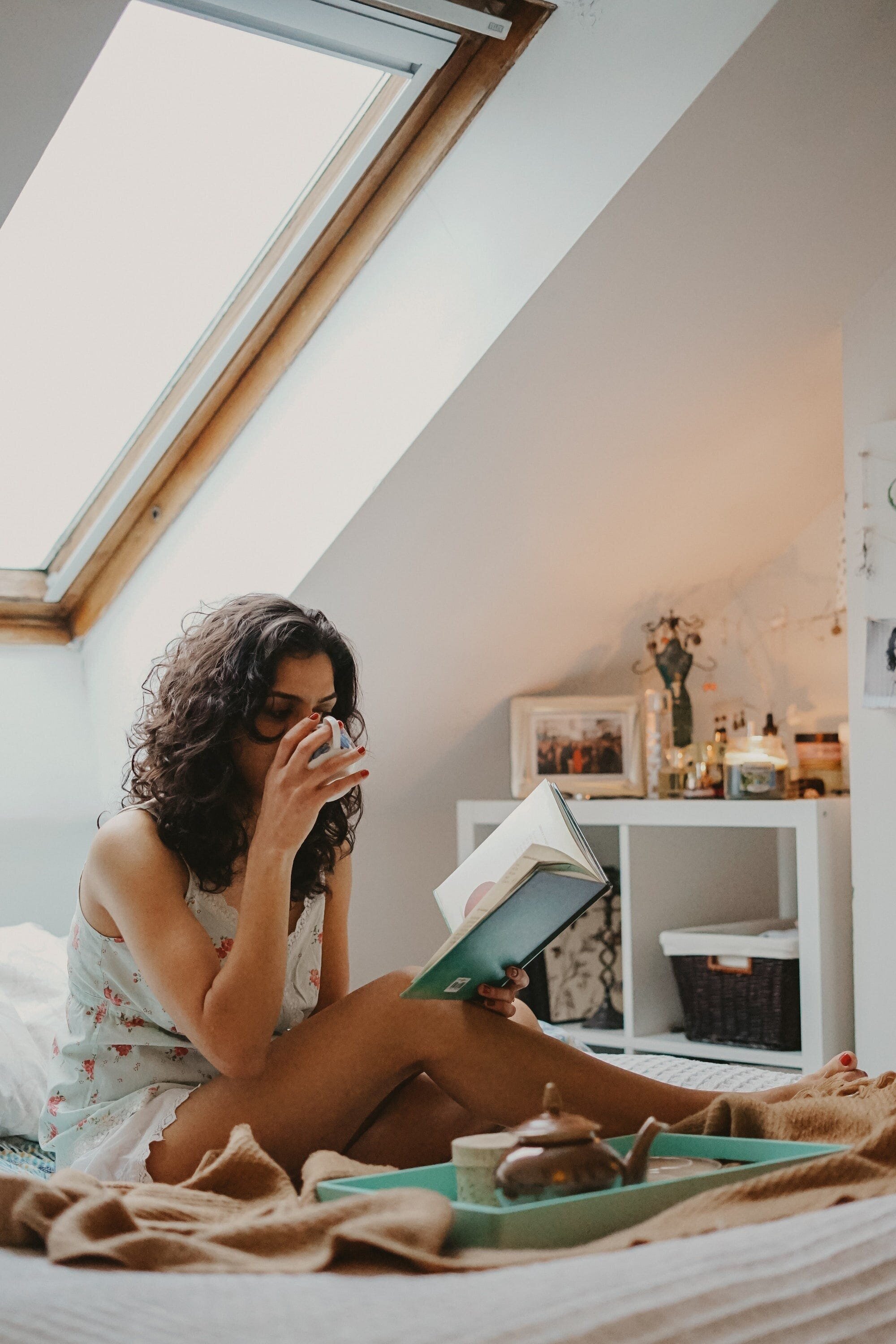 Creating a Self-Care Routine: Tips and Tricks for a Happier, Healthier You 3 | Mania Africa | maniainc.com A woman reading a book in bed while drinking Chai