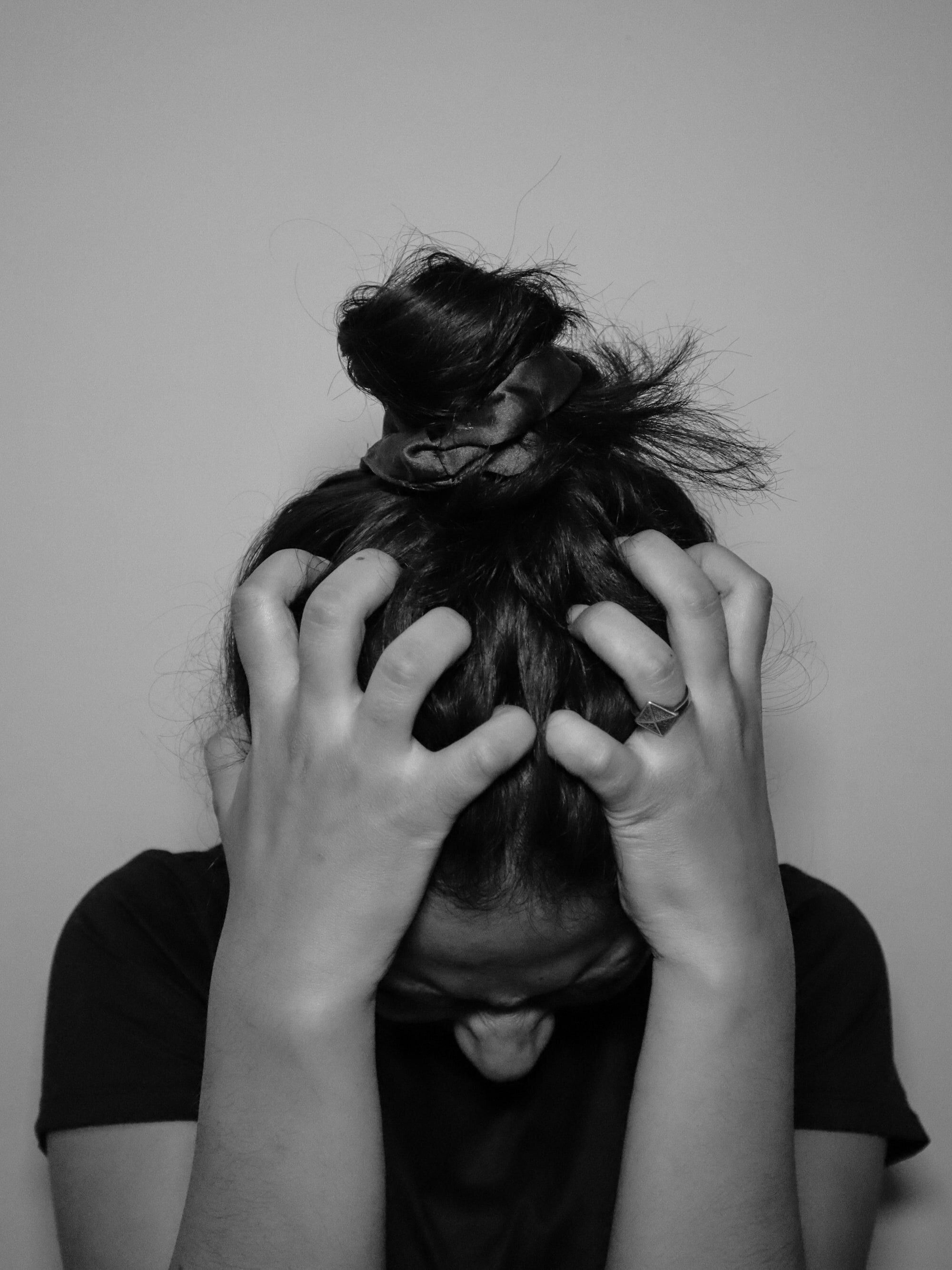 Exploring the Power of Thought: From Brain-Machine Interfaces to Genetics and Aging 5 | Mania Africa | maniainc.com A photo of a woman with her head in her arms and an unhappy expression on her face due to stress