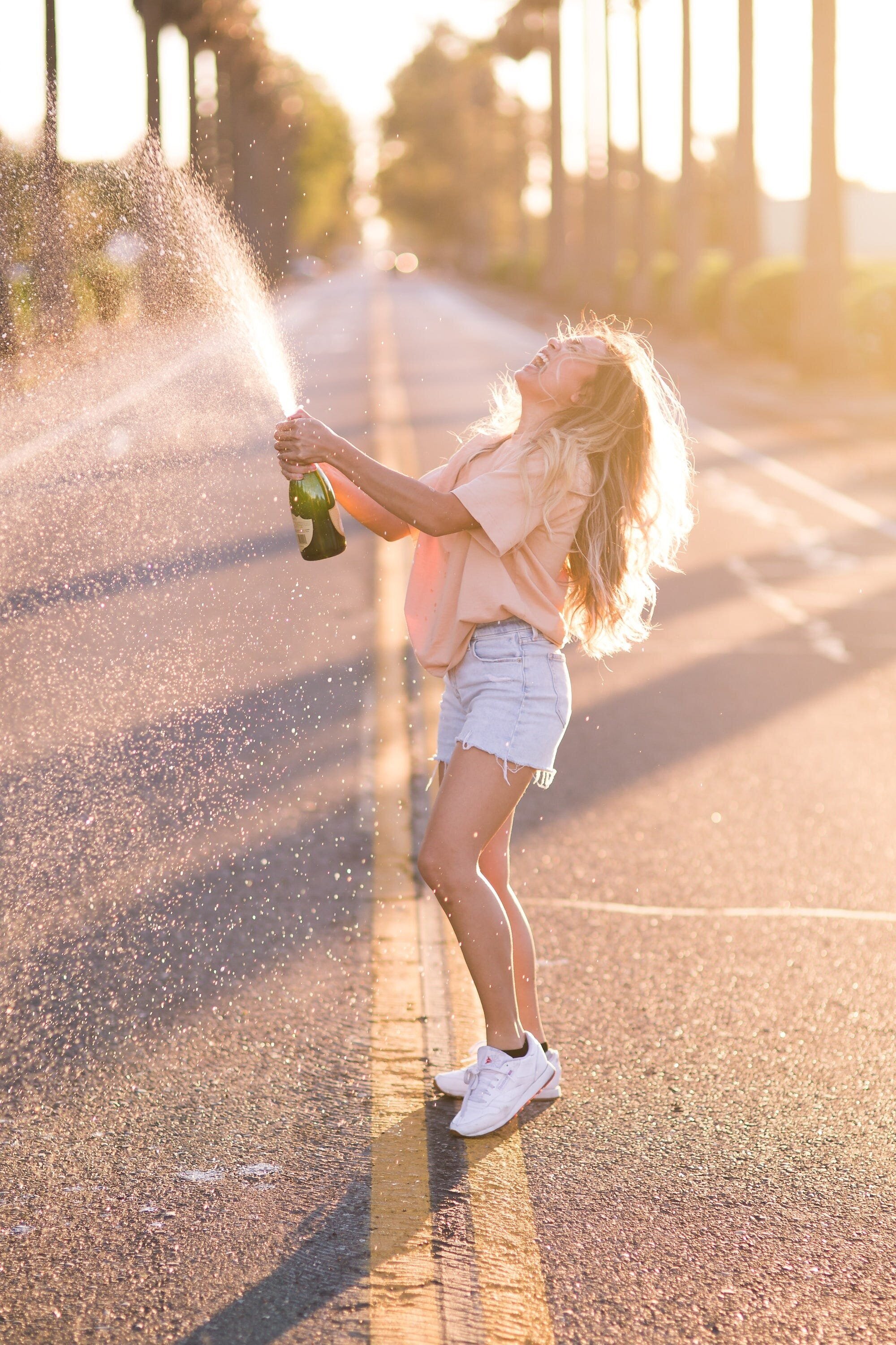 Are Happiness and Life Transient? Examining the Debate and the Role of Perspective 2 | Mania Africa | maniainc.com A woman popping a bottle of champagne on the road while happily shouting out