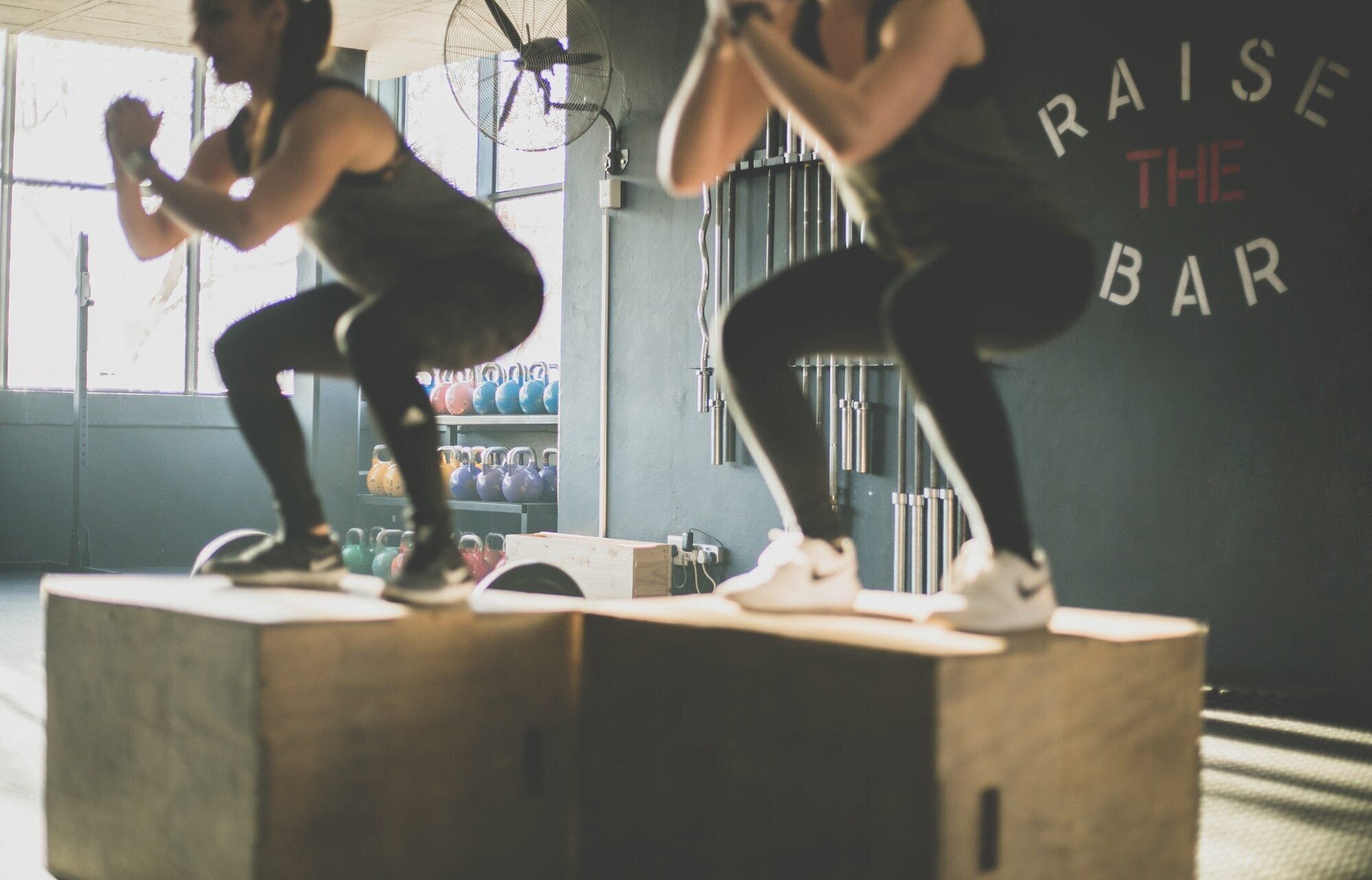 The Ultimate Guide to Strength Training with Free Weights for Women 4 | Mania Africa | maniainc.com Two women squating on top of wooden blocks in a gym