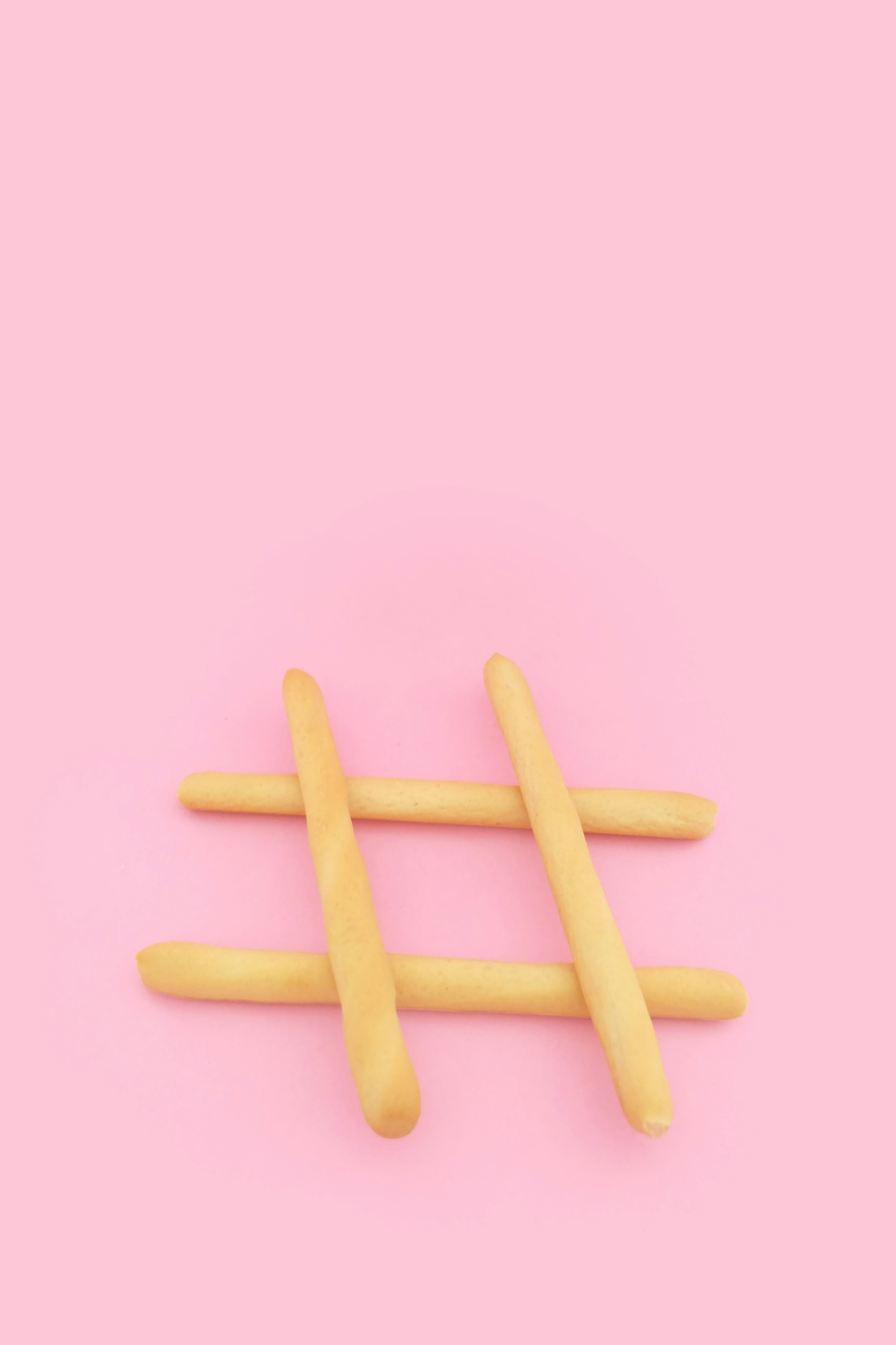The Ultimate Guide to Content Marketing and Website Promotion: Tips, Hacks, and Useful Advice 15 | Mania Africa | maniainc.com four brown wooden sticks on pink surface resembling a hashtag # | How Can I Make Daily With My Website or App? | Affiliate Marketing as Part of Content Marketing | Mania Guides