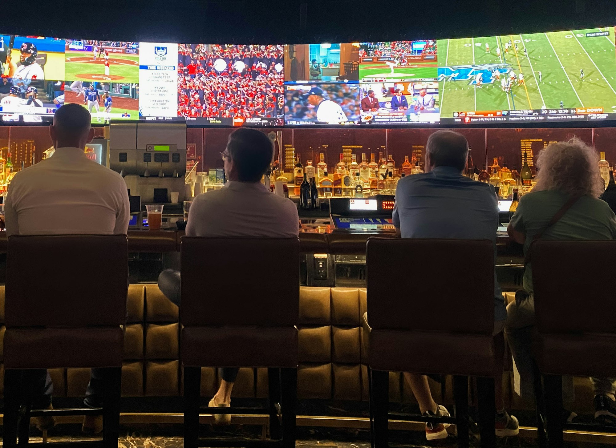 The Hidden Costs of Europe's Digital Gambling Explosion: Addiction, Exploitation, and the Quest for Reforms 2 | Mania Africa | maniainc.com a group of people sitting at a bar watching sports on tv | The rapid growth of digital gambling in Europe was propagated by the emergence of digital technologies allowing anyone to place bets online | Mania Sports