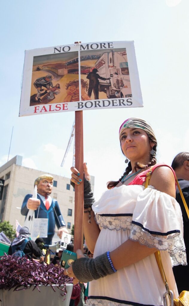 How Trump's White House Return Could Reshape Immigration Policy 4 | Mania Africa | maniainc.com A protestor holding a sign that reads 'No More False Borders' during a protest against Trump's anti-immigration policies