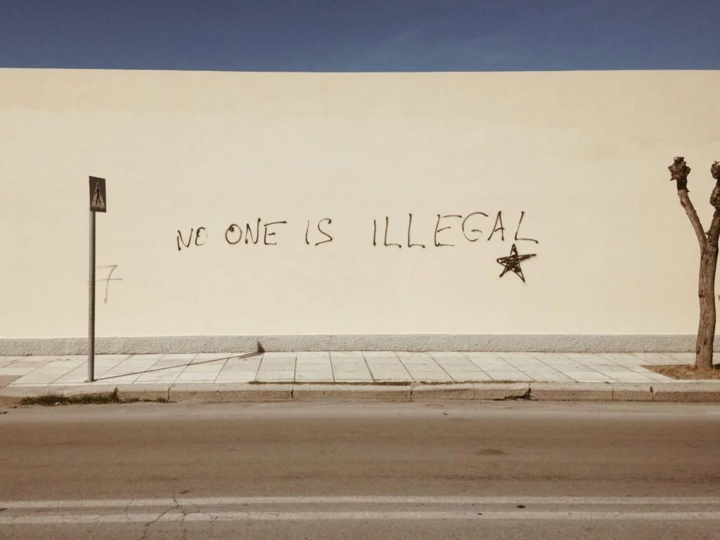 How Trump's White House Return Could Reshape Immigration Policy 2 | Mania Africa | maniainc.com Graffiti on a wall reading "No one is Illegal" - How Trump's White House Return Could Reshape Immigration Policy - Mania News